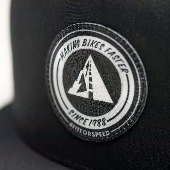 Profile Design Black cap with a circular logo featuring text and a triangle design.